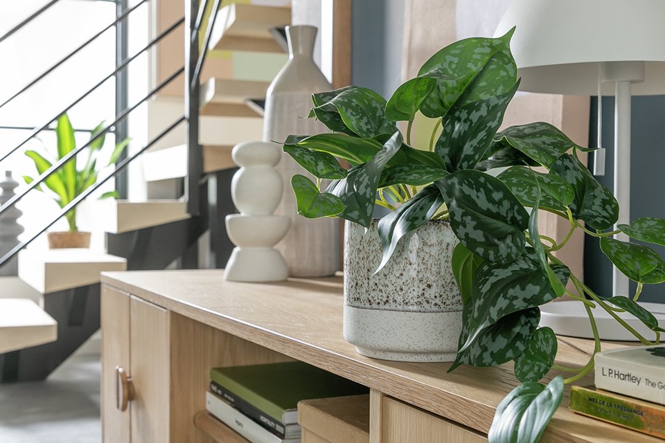 Faux plant in cream pot on side table.