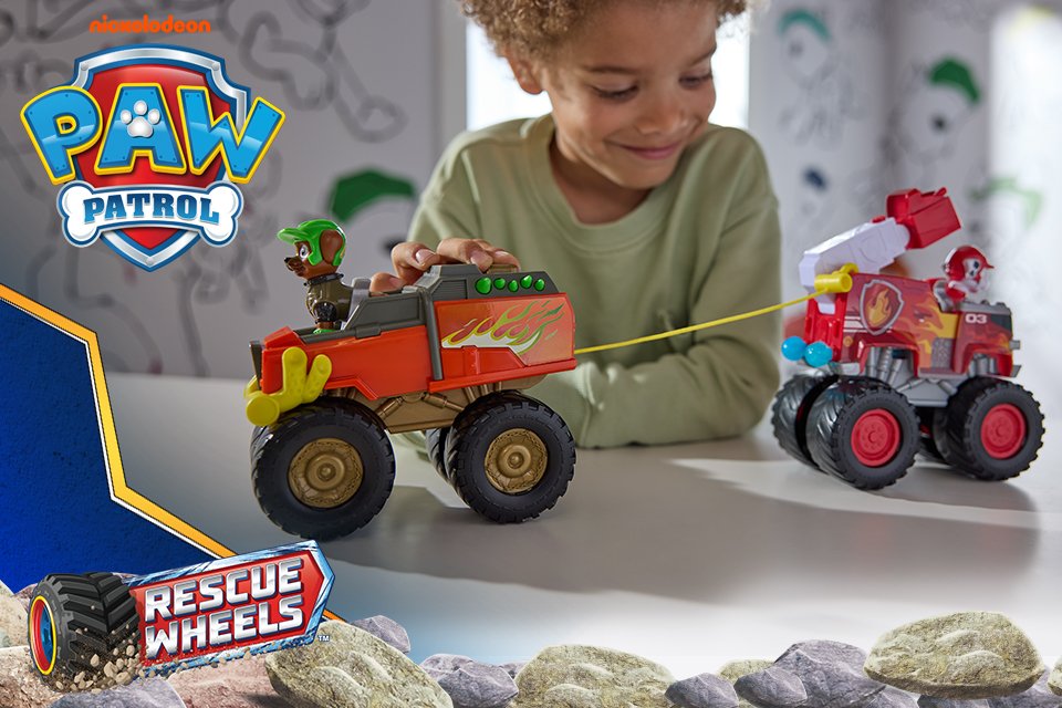 A child playing with two PAW Patrol Rescue Wheels vehicles with characters riding them.