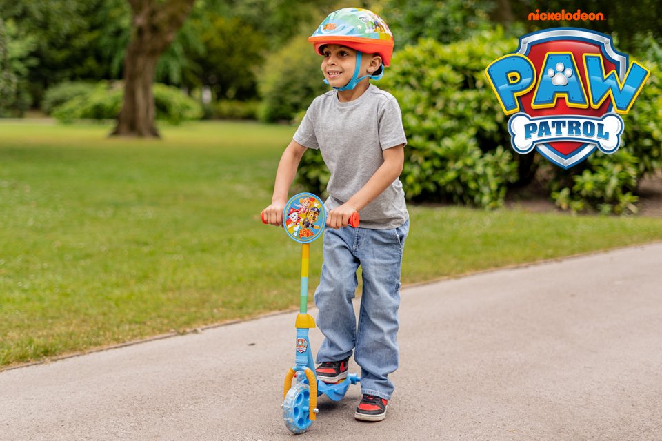 A little boy riding a PAW Patrol scooter.
