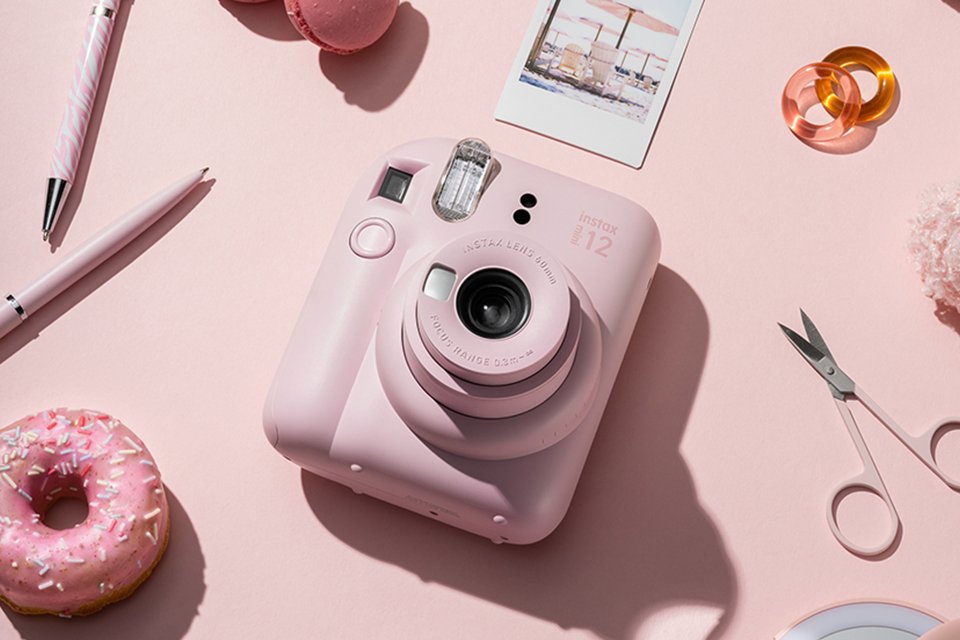 A pink instax™ mini 12 instant camera placed on a pink background.