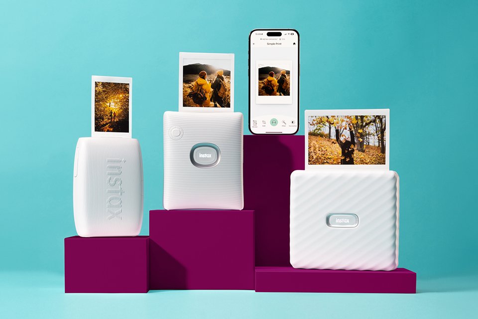 Various white instax™ smartphone photo printers placed on a burgundy podium.