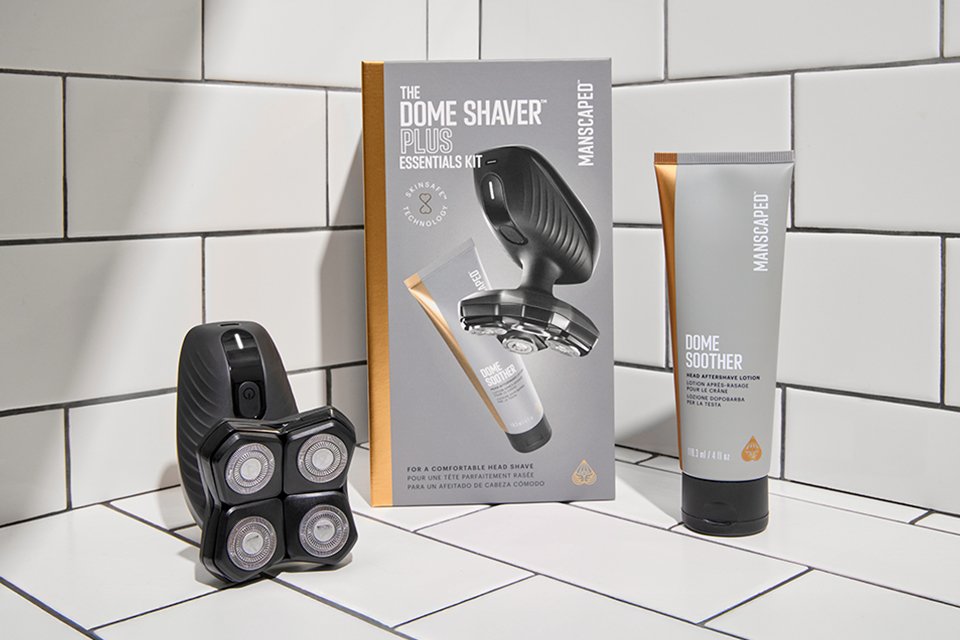 Shot of the products from Manscaped Dome Shaver Plus Essentials kit laid out on white tiles.
