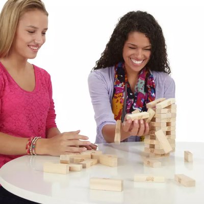 Three teenagers playing Jenga The Original Board Game from Hasbro Gaming.