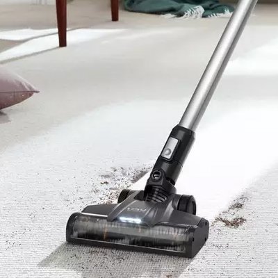 A man using Vax Blade 4 Classic Cordless Vacuum Cleaner to clean under a sideboard.