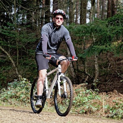 A man riding Cross FXT30 26 inch Wheel Size Mens Mountain Bike.