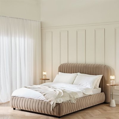 Cloud cream lined bedframe with white bedding in large room painted white.