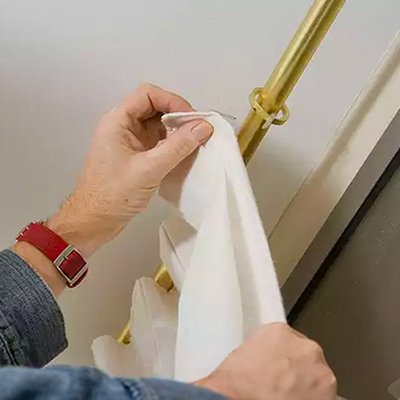 Person putting up curtains on a curtain pole.