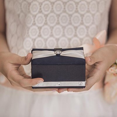 A woman in a wedding gown holding a gift box.