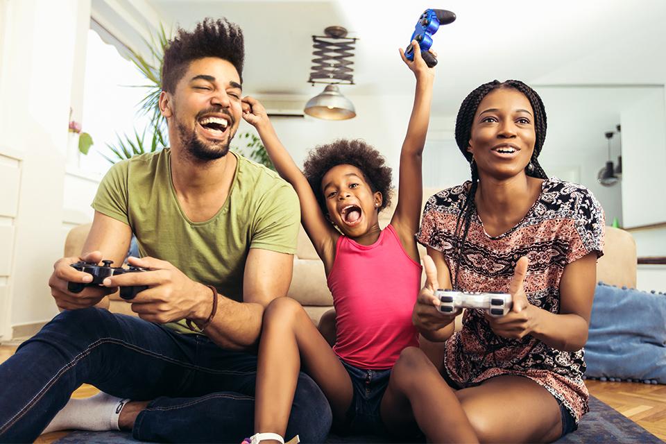 A girl enjoys playing video games with her parents.
