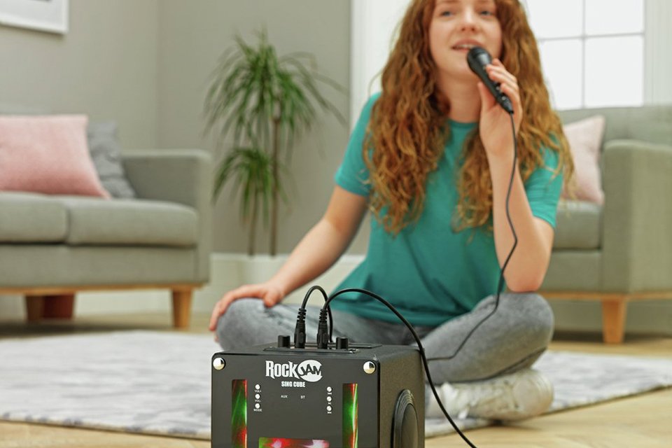 Girl sitting on floor singing karaoke.
