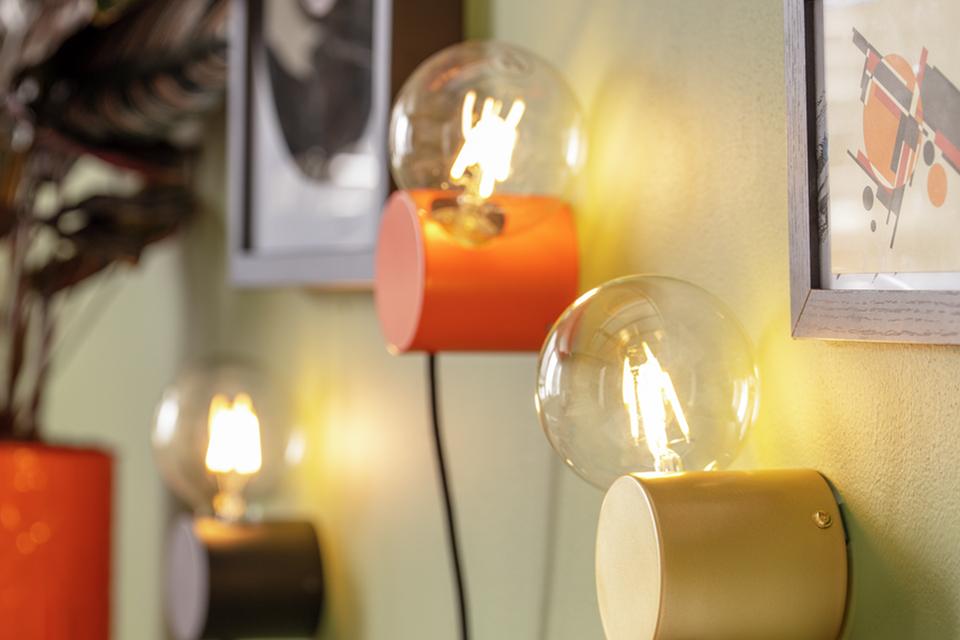 Trio of retro wall lights in orange, yellow and grey.