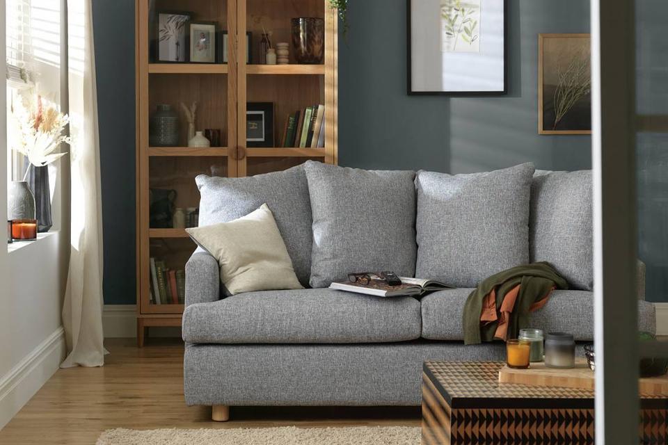 Image of a living room with a small sofa, rug and armchair.