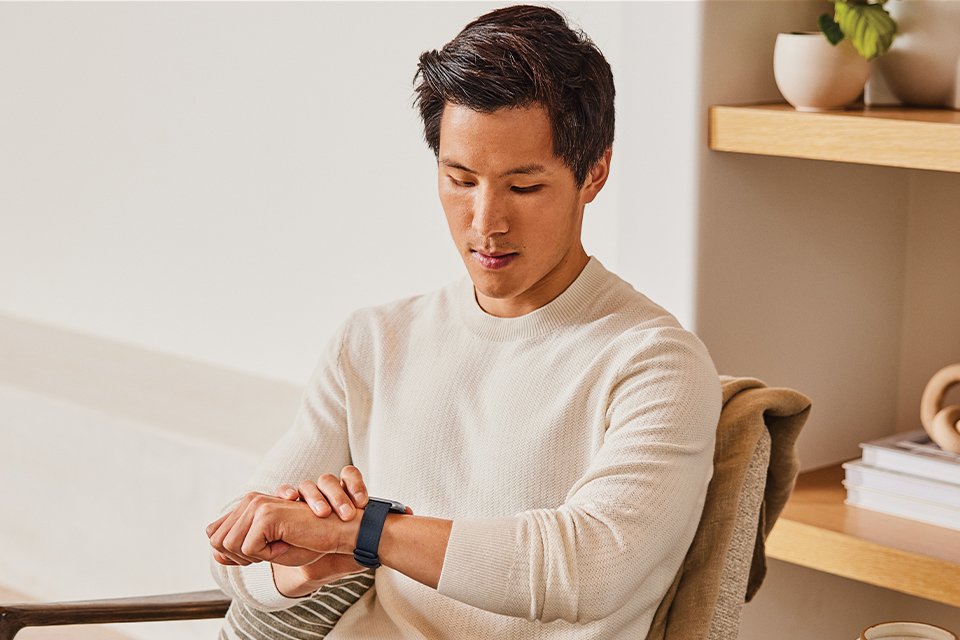 Man sitting and looking at his Fitbit watch.