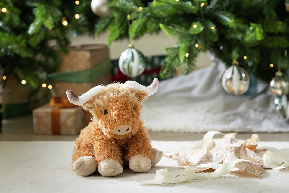 An Argos Home Highland cow hottie under a Christmas tree.