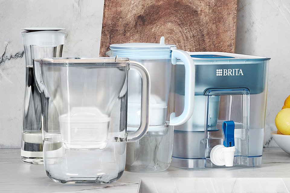 A BRITA carafe, glass jug and flow tank on a kitchen worktop with other things.