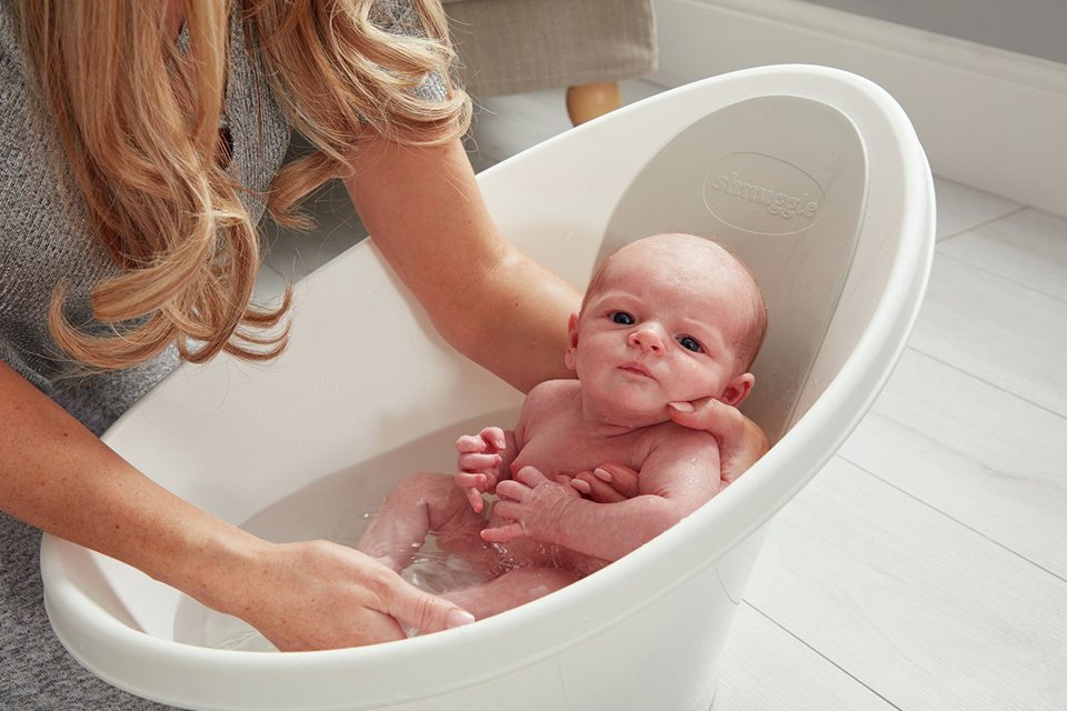 A baby being bathed in a Shnuggle Baby Bath.