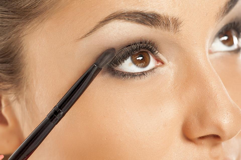 Woman applies eyeliner above her eyelashes.