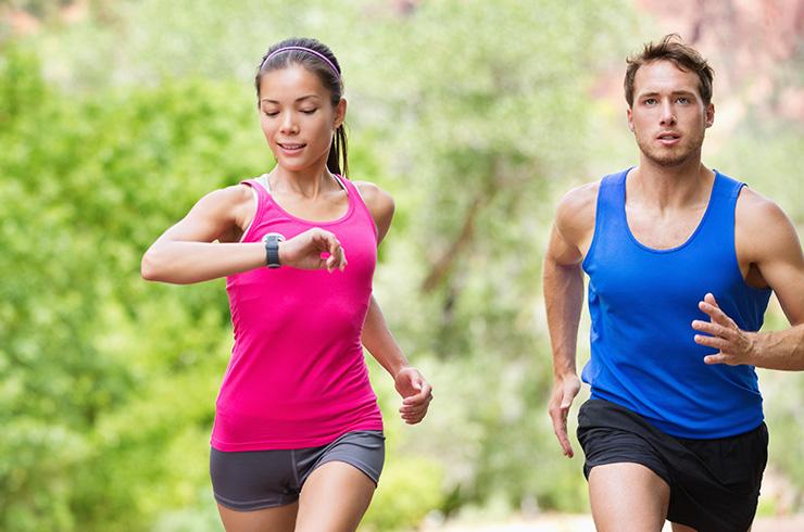 Two people running, wearing fitness watches.