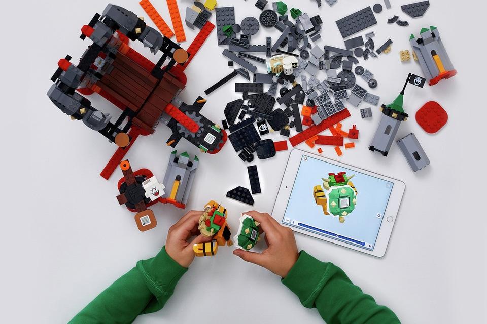 An overhead image of spread out LEGO, with an instruction manual shown on a tablet.