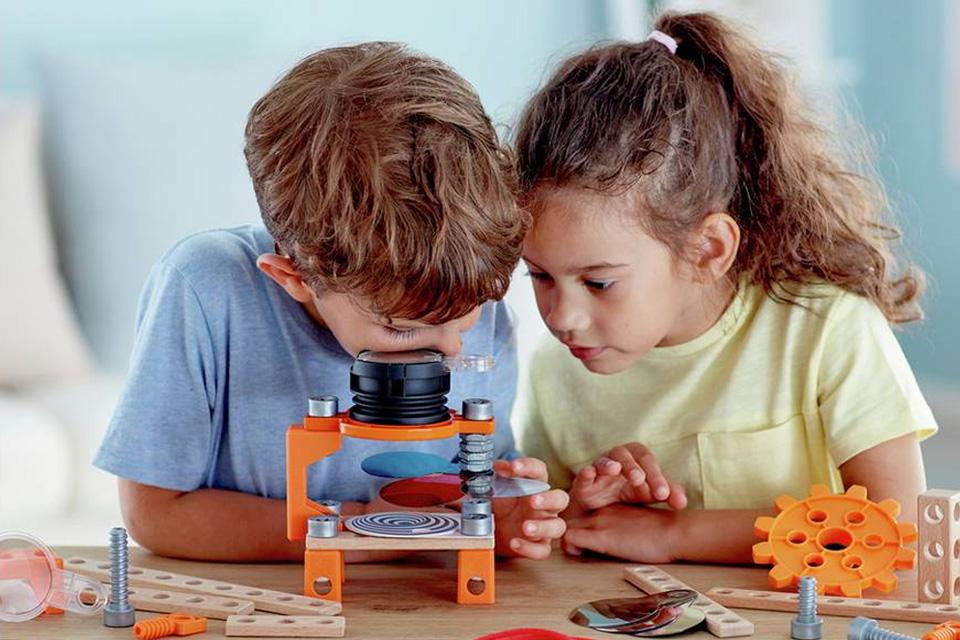 A boy and girl taking turns to view an optical illusion kit.