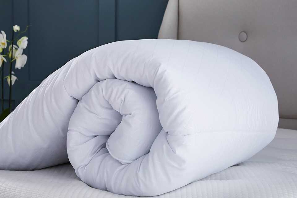 Image of a thick winter duvet rolled up on a bed.