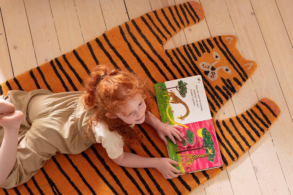Image of a kid laying on a rug that looks like a tiger.