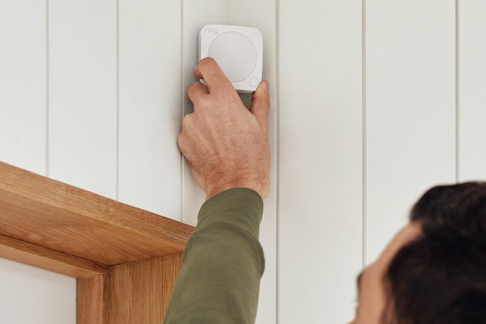 Man putting Ring Alarm Motion Detector in the corner of a room.