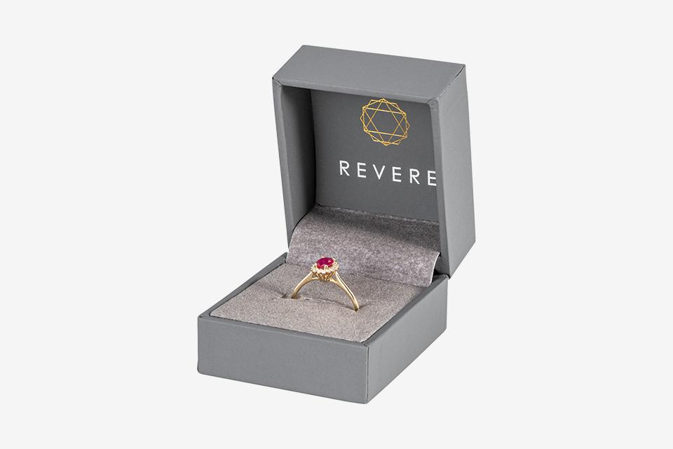 Gold engagement with ruby in presentation box.