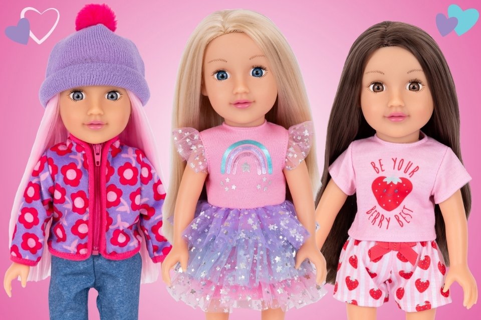 Three 14-inch Little Sister DesignAfriend dolls dressed in different outfits, posed side by side on a pink background with hearts. 