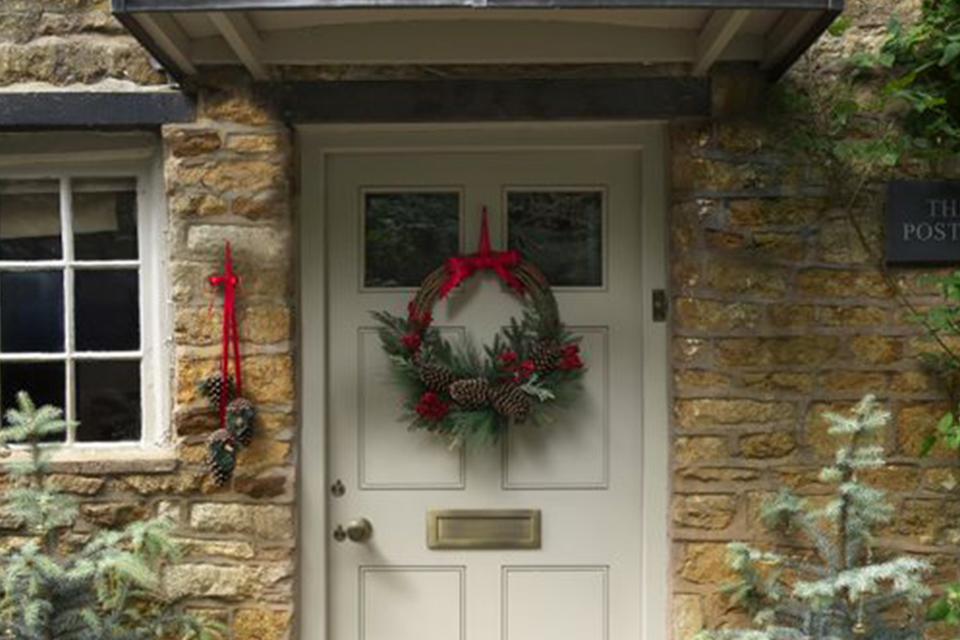 A white front door of a house decorated with a wreath.