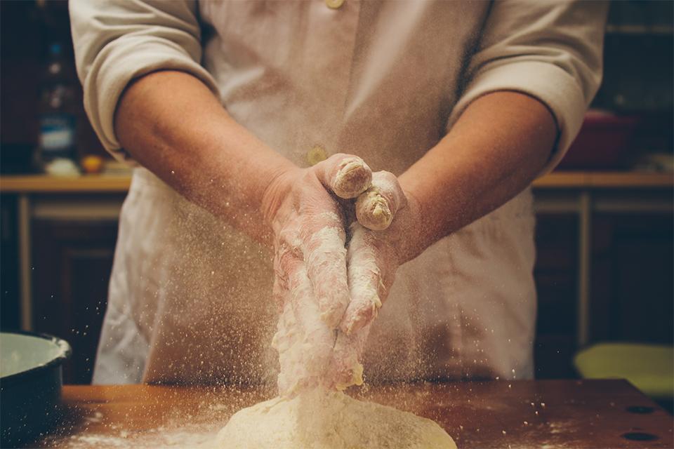 Chef clapping hands full of flour over fresh dough.
