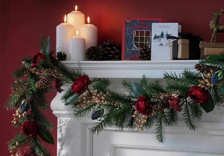 Image of a festive wreath hanging from a mantelpiece in a red living room.