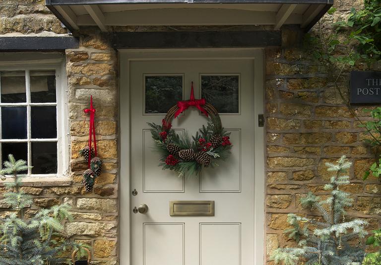 Image of a Christmas door wreath on the front door of a cottage.