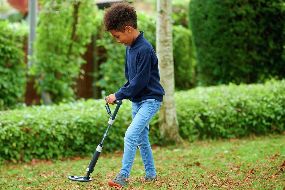A boy using Science Mad Digital Metal Detector STEM toy outdoor.
