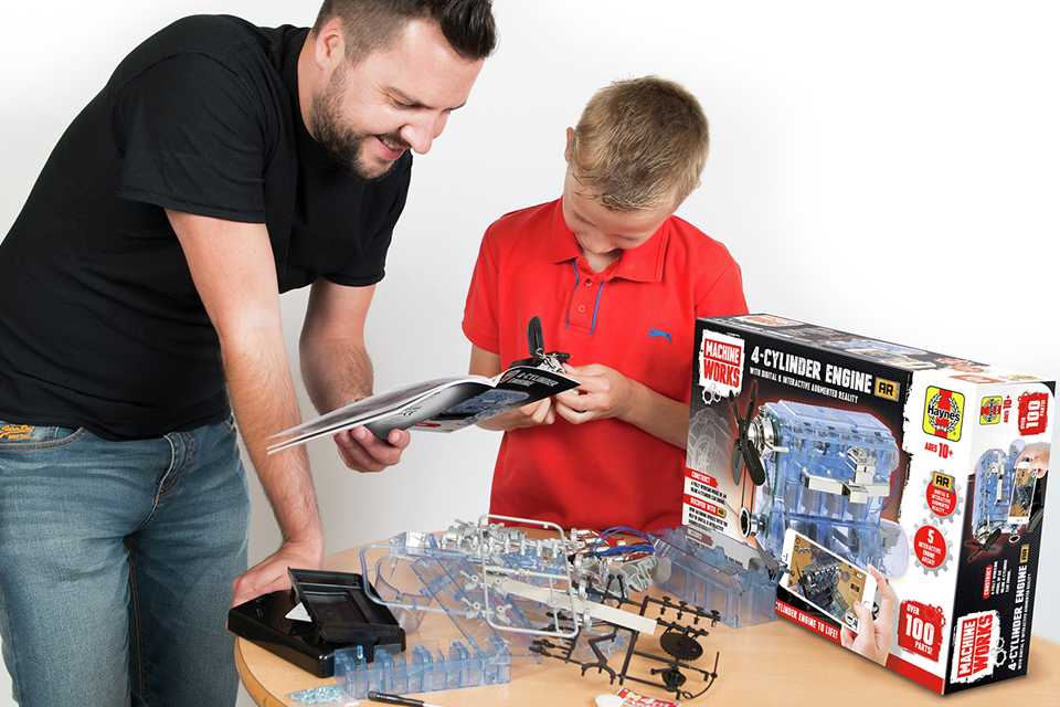 A father and son playing with Haynes Build Your Own Internal Combustion Engine STEM toy.