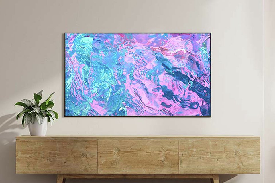 A TV mounted on a wall over a wooden finish TV unit.