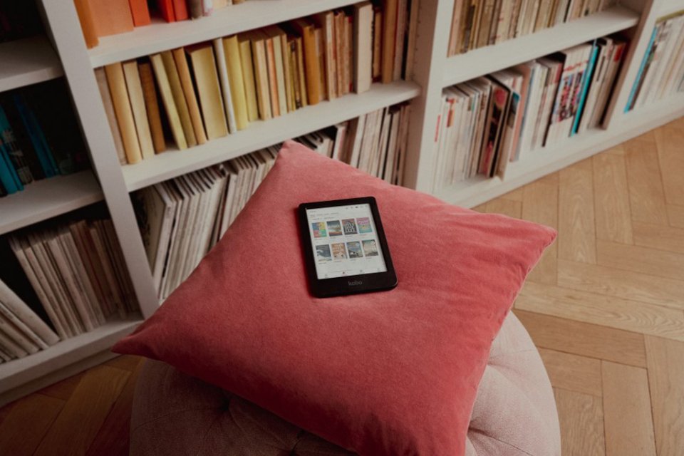 A Rakuten Kobo eReader placed on a cushion in a library.