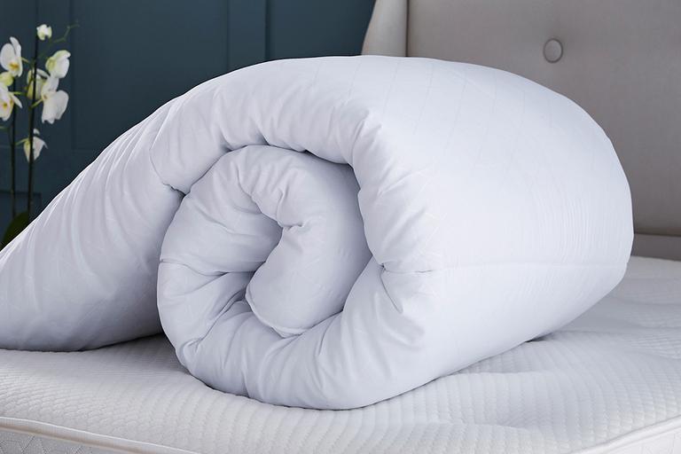 Duvet rolled up on a bed.