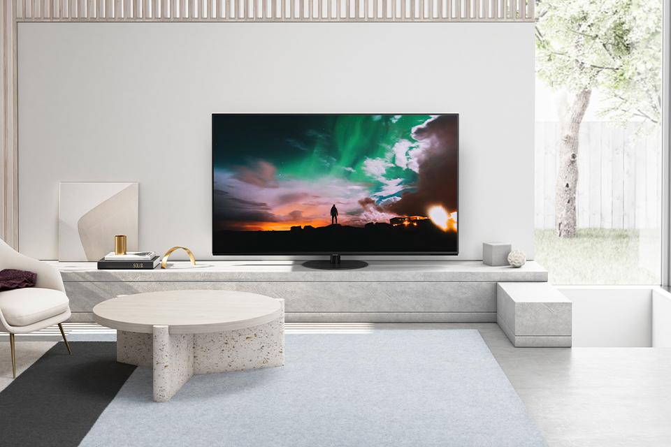 Image shows a Panasonic JZ980 television screen in a cosy, neutral living room.