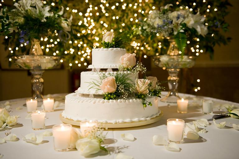 A beautiful wedding cake surrounded by white candles.