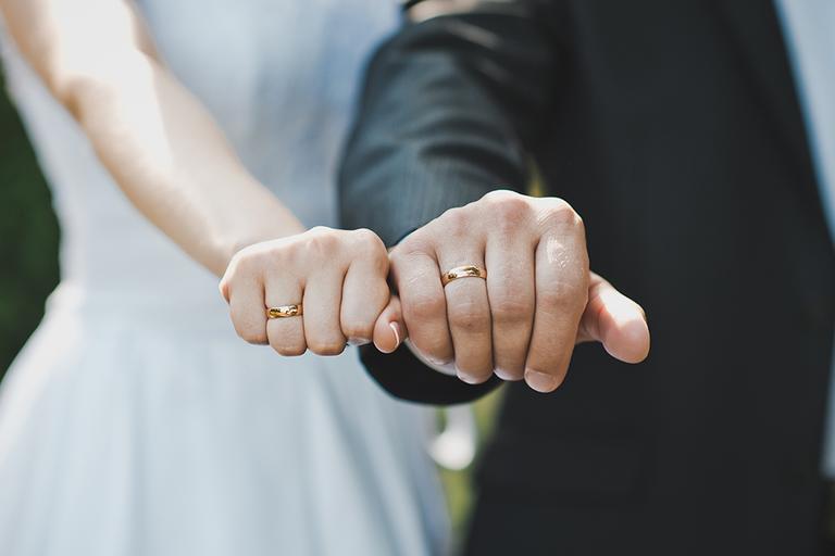 A couple showing their gold wedding rings.
