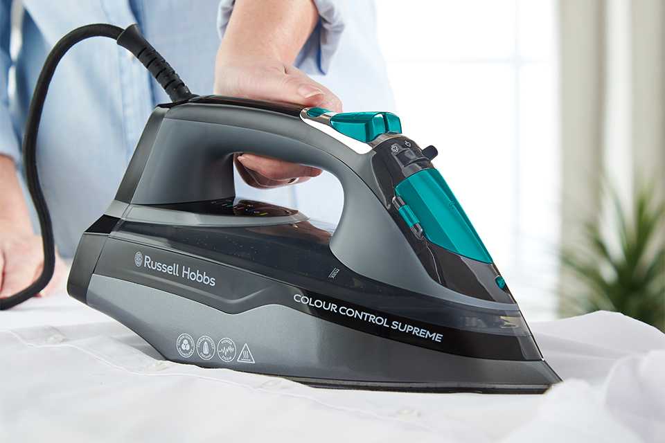 Dark grey Russell Hobbs iron with teal accent ironing a cloth.