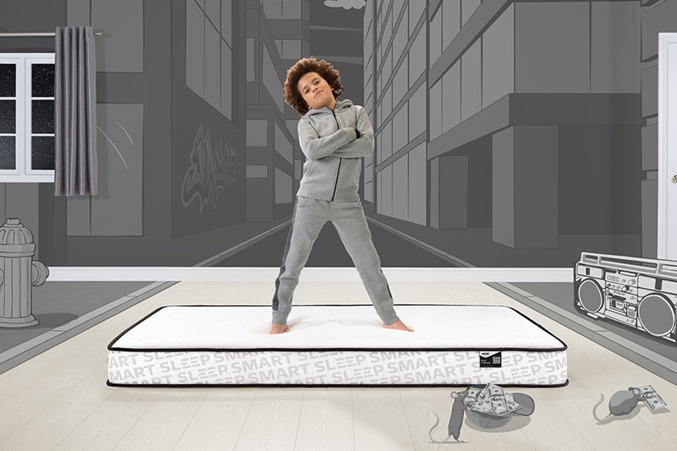 A kid standing on a Jay-Be® Bunk mattresses with folded arms.