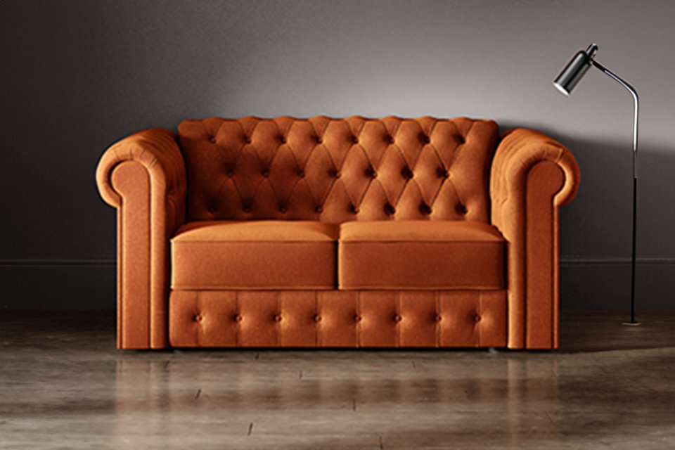 An orange Jay-Be® Chesterfield sofa bed in a living room setup.
