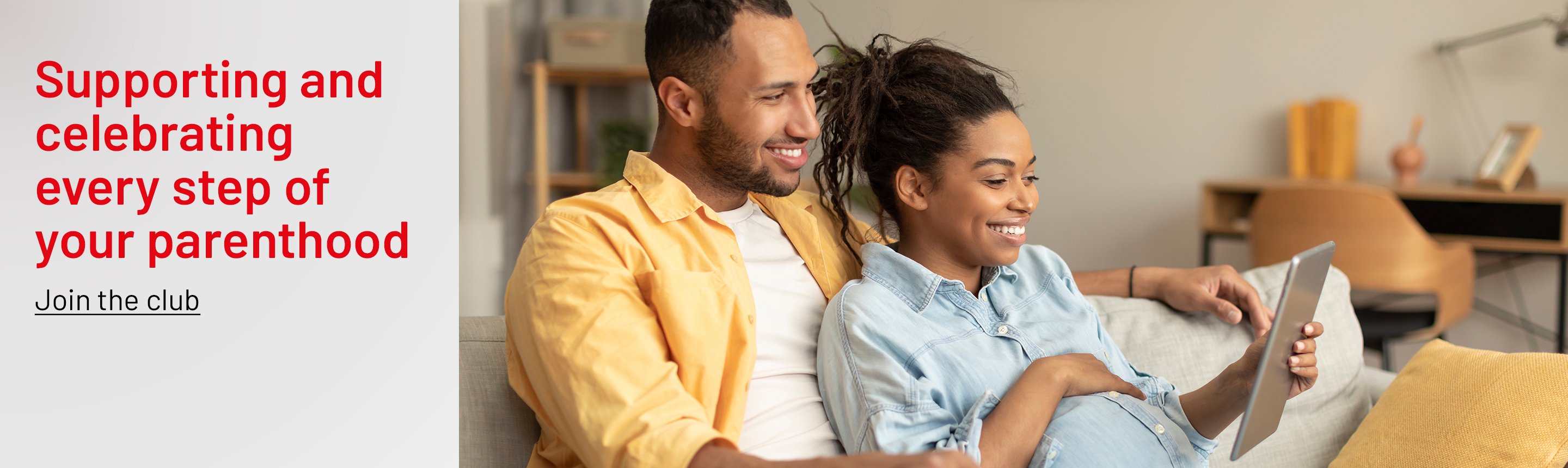 A pregnant couple looking at a tablet for baby related information.
