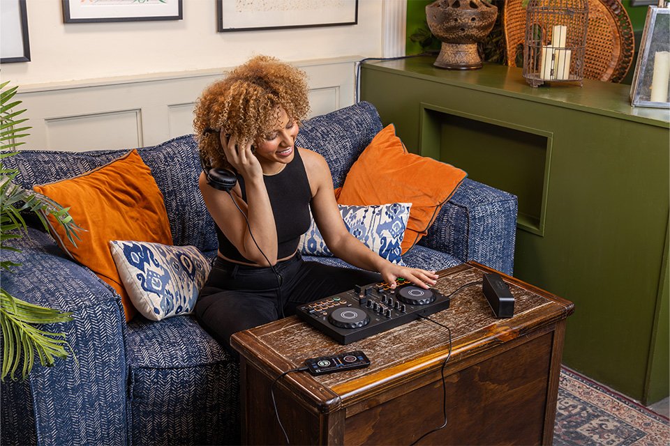A woman using a Pioneer DJ controller in her living room table.