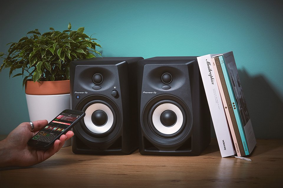 A set of two Pioneer black speakers kept on a book shelf.