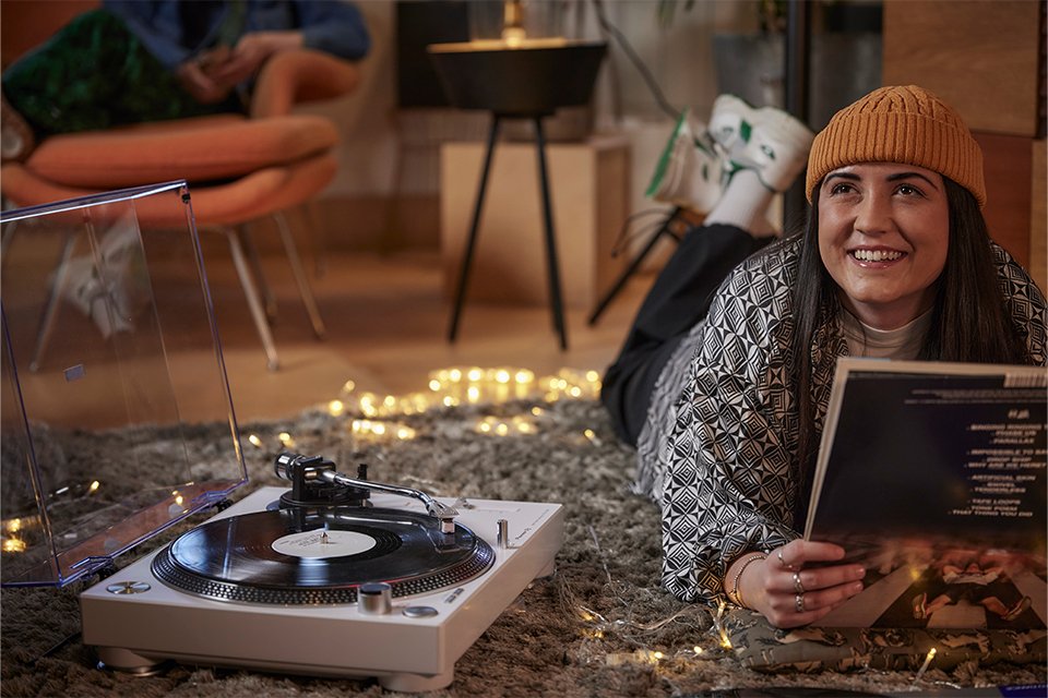 A woman listening to a record and smiling on a Pioneer DJ turntable.