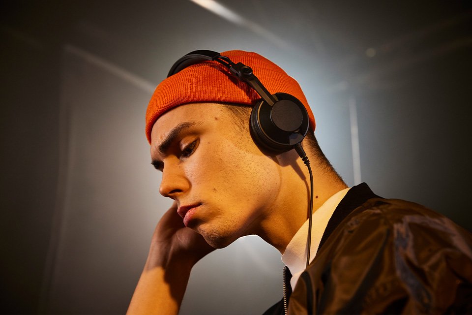 A man wearing a black Pioneer headphone and listening to music.