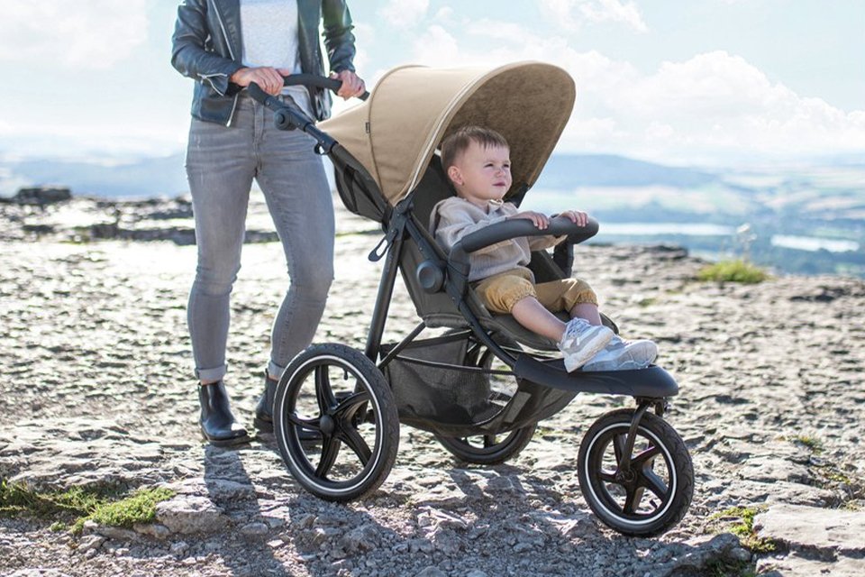 A baby in a Hauck Runner 2 Pushchair Mocha.
